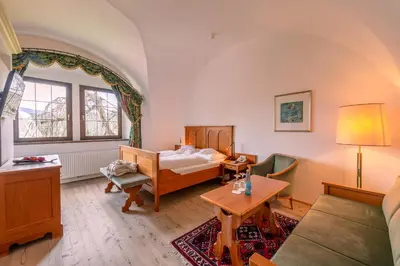 a living room with a bed and a table at Schlosshotel Aehrental in Caldaro