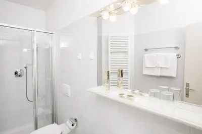 a white bathroom with a shower and a sink at Residence Désirée Classic & Design in Merano