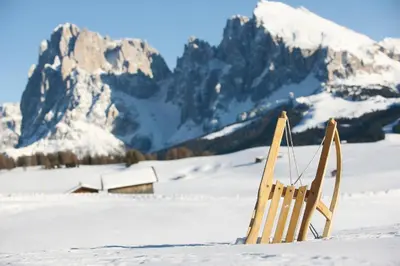 a chair sitting in the snow in front of a mountain at Residence Désirée Classic & Design in Merano
