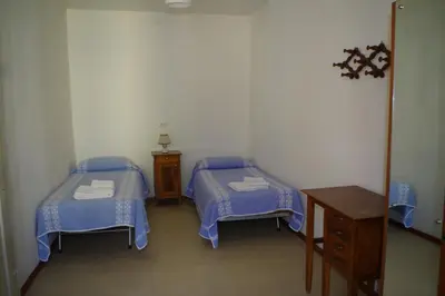 a room with two beds and a wooden table at Da Francesca in Fiera di Primiero