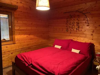 a bedroom with a red bed in a log cabin at Chalet San Valentino in Salorno sulla Strada del Vino