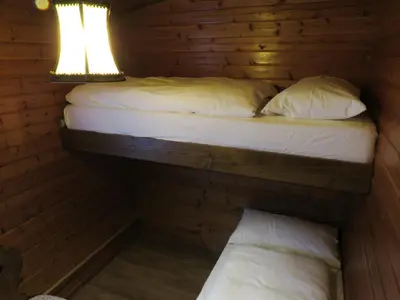 two beds in a log cabin with a lamp at Chalet San Valentino in Salorno sulla Strada del Vino