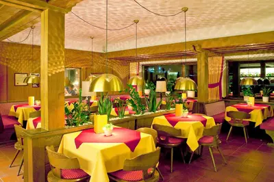 a restaurant with yellow and red tables and chairs at Hotel Markushof 3***S in Valdaora