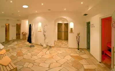 a large room with a stone floor and a hallway at Hotel Markushof 3***S in Valdaora