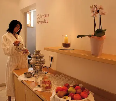 a woman standing in a room with a table with fruit at Hotel Markushof 3***S in Valdaora