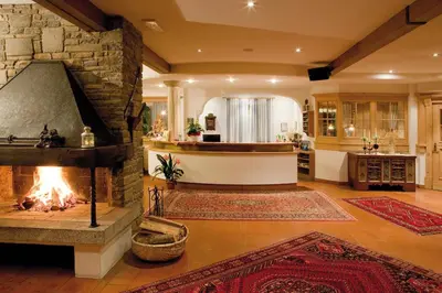a living room with a fireplace and a kitchen at Hotel Markushof 3***S in Valdaora