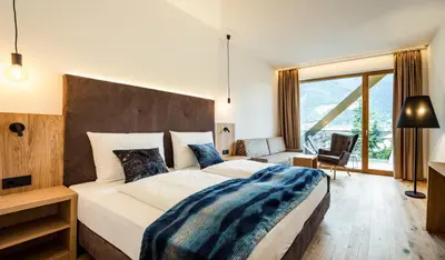 a bedroom with a large bed and a large window at Genusshotel Diamant in Naturno