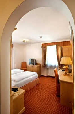 a hotel room with a bed and a desk and a television at B&B Garni Serena in Arabba