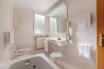 a white bathroom with a sink and a toilet at Active Hotel Malita in Arabba