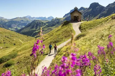 two people walking down a dirt road with flowers at Active Hotel Malita in Arabba