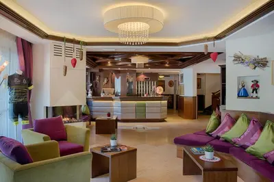 a living room with purple couches and a salon at Active Hotel Malita in Arabba