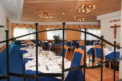 a dining room with tables and chairs and a cross on the wall at Oberwirt Weisses Kreuz in Collepietra
