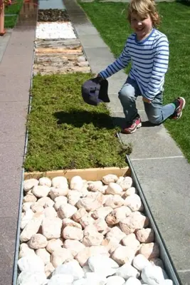 a young girl is standing next to a box of rocks at Oberwirt Weisses Kreuz in Collepietra