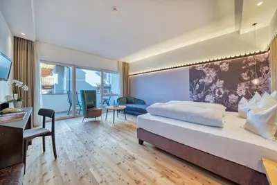 a bedroom with a large bed and a living room at Oberwirt Weisses Kreuz in Collepietra