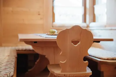 a wooden table with a wooden seat in a room at BelaVal Apartments in La Villa