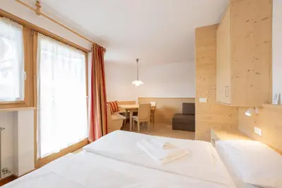 a bedroom with a bed and a dining room at BelaVal Apartments in La Villa