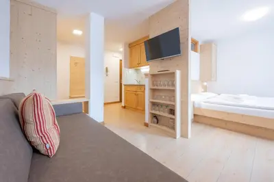 a room with a couch and a bed and a television at BelaVal Apartments in La Villa