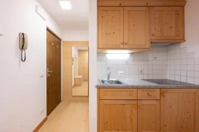 a kitchen with wooden cabinets and a sink at BelaVal Apartments in La Villa