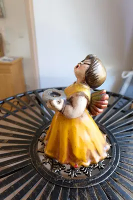 a statue of a girl in a yellow dress sitting on a table at Ferienwohnungen Villa Mirabilis in Rablà