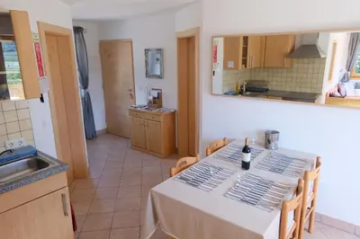 a kitchen with a table with a bottle of wine on it at Ferienwohnungen Villa Mirabilis in Rablà