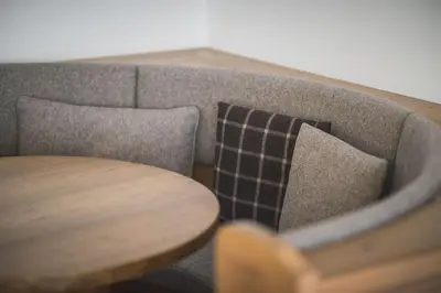 a couch with a table and a pillow on it at Hotel Alpenhof in Rasùn di Sotto