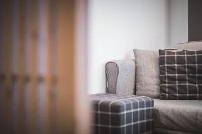 a couch with a plaid pillow sitting next to a window at Hotel Alpenhof in Rasùn di Sotto
