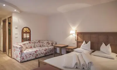 a living room with a couch and a bed at Hotel Alpenhof in Rasùn di Sotto