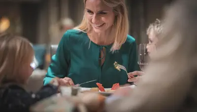a woman sitting at a table eating food at Hotel Alpenhof in Rasùn di Sotto