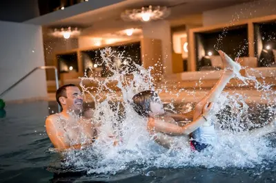 two boys playing in the water in a swimming pool at Hotel Alpenhof in Rasùn di Sotto
