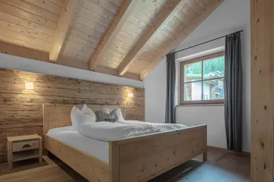 a bedroom with a large bed with a wooden wall at Chalet Ciasa Tino & Sara - BelaVal Apartments in Corvara in Badia