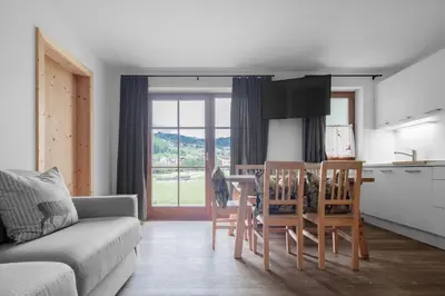 a living room with a couch and a table and chairs at Chalet Ciasa Tino & Sara - BelaVal Apartments in Corvara in Badia