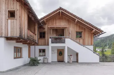 a house in the mountains with a balcony at Chalet Ciasa Tino & Sara - BelaVal Apartments in Corvara in Badia