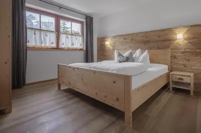 a bedroom with a large bed with white sheets and pillows at Chalet Ciasa Tino & Sara - BelaVal Apartments in Corvara in Badia