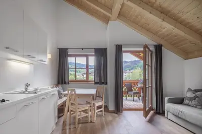 a kitchen and living room with a table and chairs at Chalet Ciasa Tino & Sara - BelaVal Apartments in Corvara in Badia