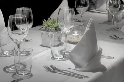 a table with wine glasses and silverware on it at Hotel Conturines in San Cassiano
