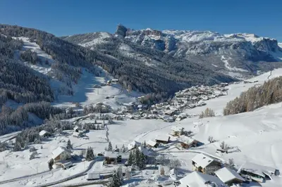 a small village in the snow with mountains at Hotel Conturines in San Cassiano