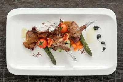 a plate of food with meat and vegetables at Hotel Conturines in San Cassiano
