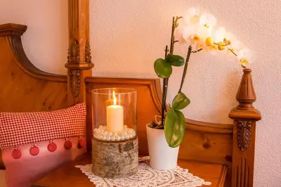 a candle and a vase with flowers on a table at Hotel Table in Corvara in Badia