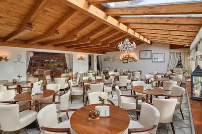a restaurant with wooden ceilings and tables and chairs at Hotel Table in Corvara in Badia
