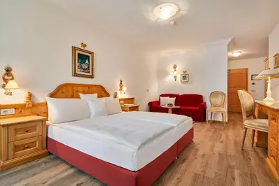 a bedroom with a large bed and a red chair at Hotel Table in Corvara in Badia
