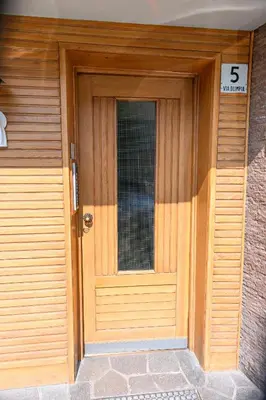 a wooden front door of a house with the number at Casa Olimpia in Cortina dʼAmpezzo
