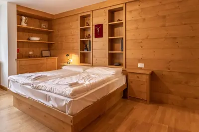 a bedroom with a bed in a wooden wall at Casa Alverà in Cortina dʼAmpezzo