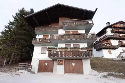 a building with wooden doors and balconies on it at Casa Alverà in Cortina dʼAmpezzo