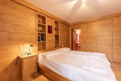 a bedroom with wooden walls and a white bed at Casa Alverà in Cortina dʼAmpezzo