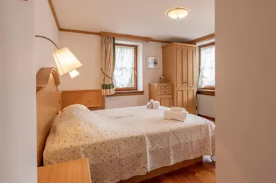 a bedroom with a bed with a white blanket at Casa Do Sol in San Vito di Cadore