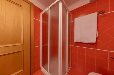 a red tiled bathroom with a shower and a towel at Casa Do Sol in San Vito di Cadore