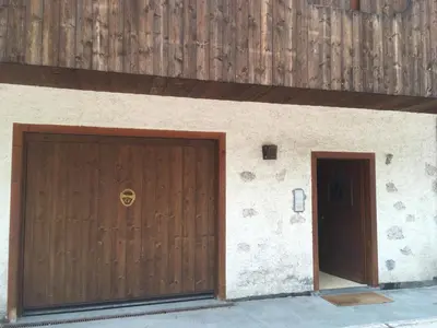 a garage with a brown door and a wall at Casa Do Sol in San Vito di Cadore