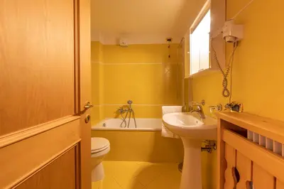 a yellow bathroom with a sink and a toilet at Casa Do Sol in San Vito di Cadore
