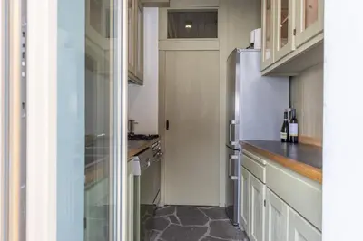 a kitchen with white cabinets and a refrigerator at Casa Majon in Cortina dʼAmpezzo