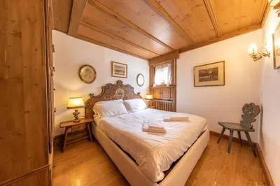 a bedroom with a bed in a room with wooden ceilings at Casa Pecol in Cortina dʼAmpezzo
